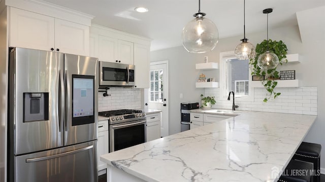 kitchen with a sink, appliances with stainless steel finishes, a peninsula, white cabinetry, and open shelves