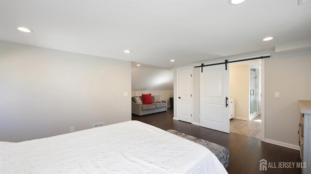 bedroom featuring wood finished floors, visible vents, baseboards, recessed lighting, and a barn door