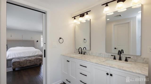 bathroom featuring a sink, visible vents, wood finished floors, and ensuite bath