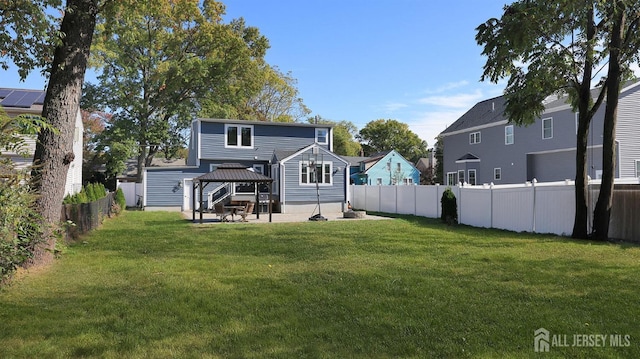 rear view of property with a gazebo, a yard, a patio, and a fenced backyard