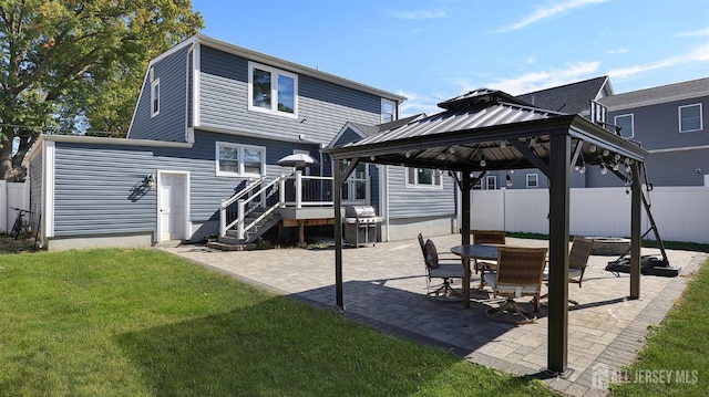 rear view of property featuring a gazebo, a patio, a lawn, and fence