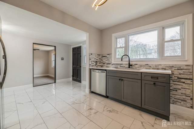 kitchen featuring a sink, plenty of natural light, baseboards, dishwasher, and marble finish floor