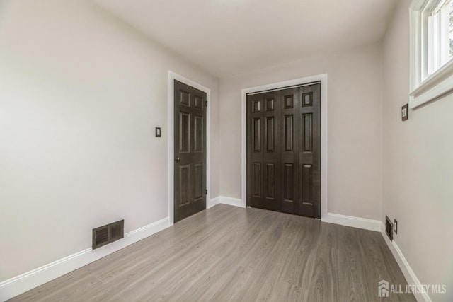 interior space featuring baseboards, visible vents, and wood finished floors