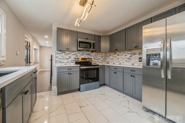 kitchen featuring stainless steel appliances, marble finish floor, recessed lighting, light countertops, and gray cabinetry
