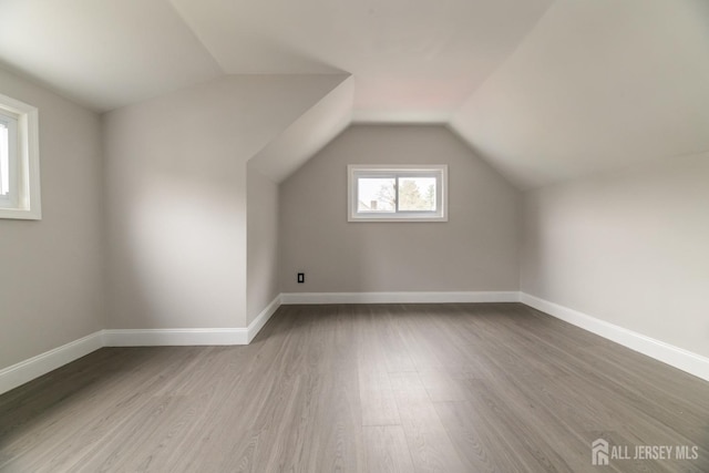 additional living space with vaulted ceiling, baseboards, and wood finished floors