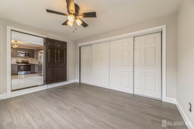 unfurnished bedroom with a closet, stainless steel fridge, light wood-style flooring, and baseboards