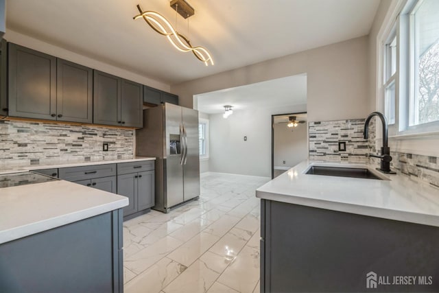 kitchen featuring marble finish floor, decorative backsplash, a sink, and stainless steel refrigerator with ice dispenser