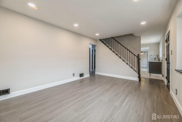 unfurnished living room featuring stairway, visible vents, recessed lighting, and wood finished floors