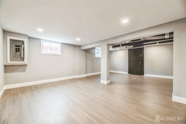 basement featuring baseboards, recessed lighting, electric panel, and wood finished floors