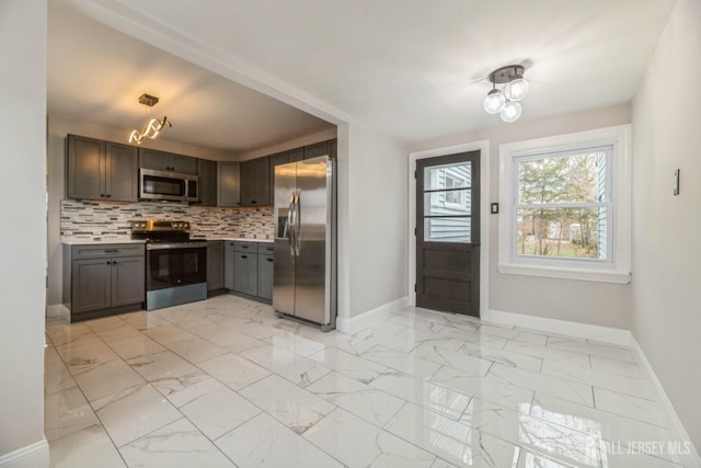kitchen featuring stainless steel appliances, baseboards, light countertops, and decorative backsplash