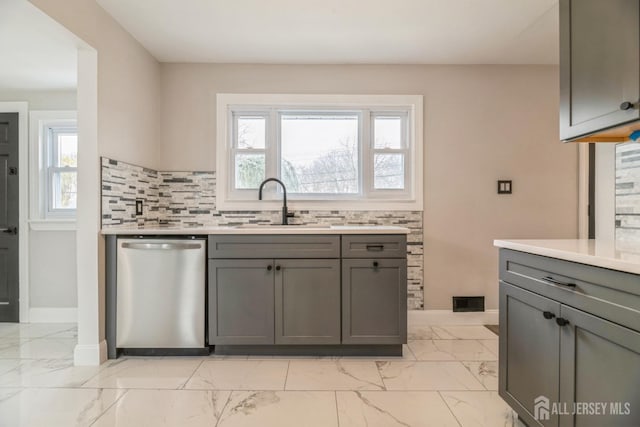 kitchen featuring marble finish floor, gray cabinetry, a sink, and dishwasher