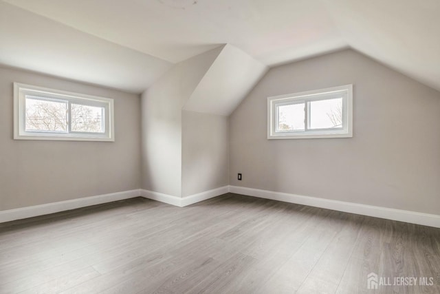 additional living space featuring vaulted ceiling, wood finished floors, and baseboards