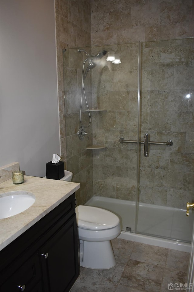 bathroom with vanity, toilet, tile patterned floors, and a shower with door