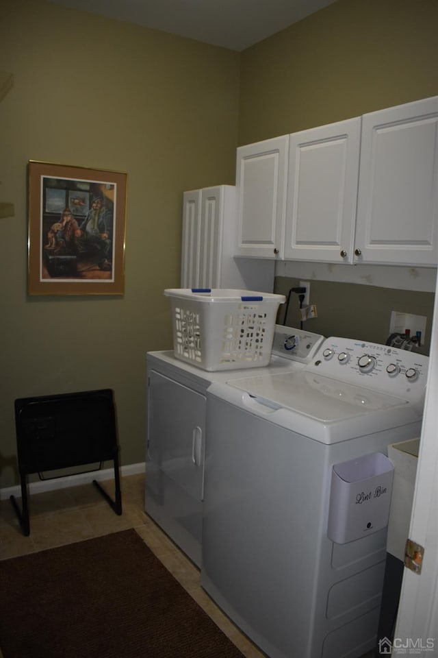 clothes washing area featuring washing machine and dryer, cabinets, and light tile patterned floors