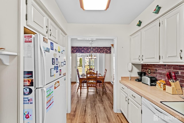 kitchen featuring light wood-style flooring, white appliances, an inviting chandelier, white cabinets, and light countertops