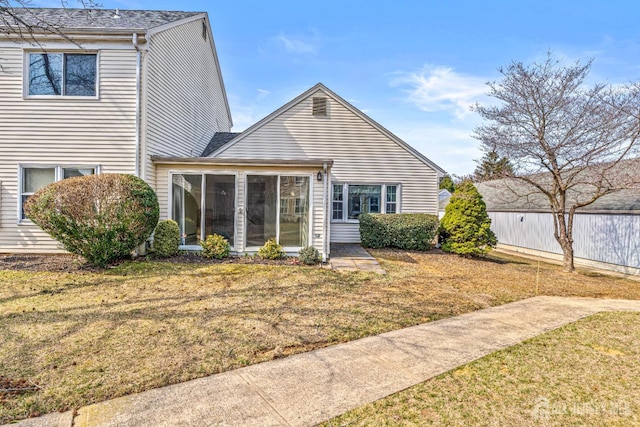 rear view of property featuring a lawn and a sunroom