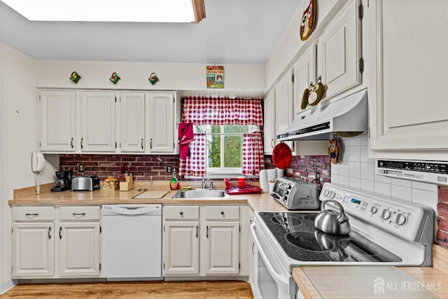 kitchen featuring white appliances, a sink, light countertops, white cabinets, and under cabinet range hood