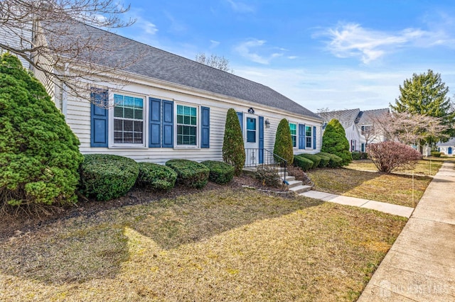 view of front of property with roof with shingles and a front yard