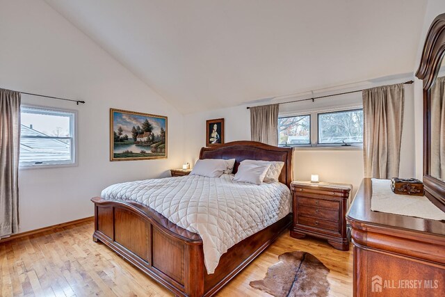 bedroom with light wood-type flooring, multiple windows, and vaulted ceiling