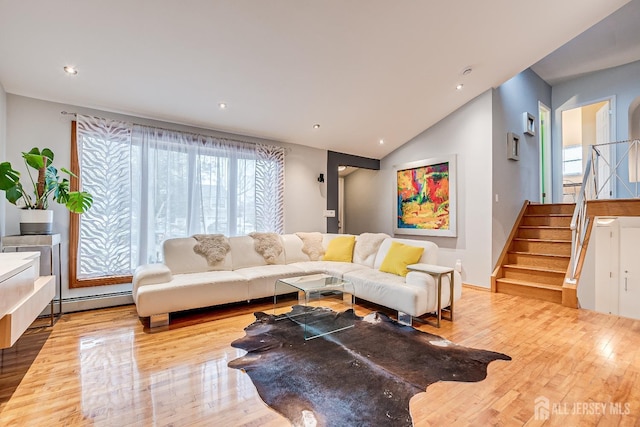 living room with a baseboard heating unit, vaulted ceiling, and light wood-type flooring