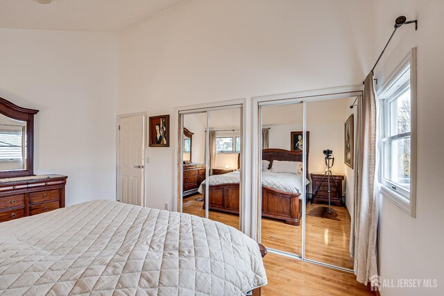 bedroom featuring light hardwood / wood-style floors and multiple closets