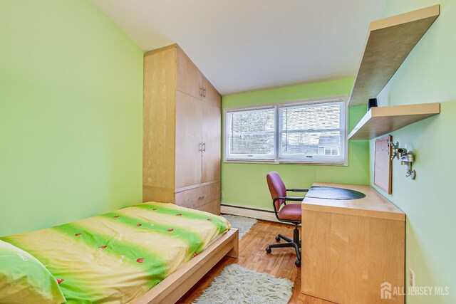 bedroom featuring lofted ceiling, a baseboard radiator, and light hardwood / wood-style floors