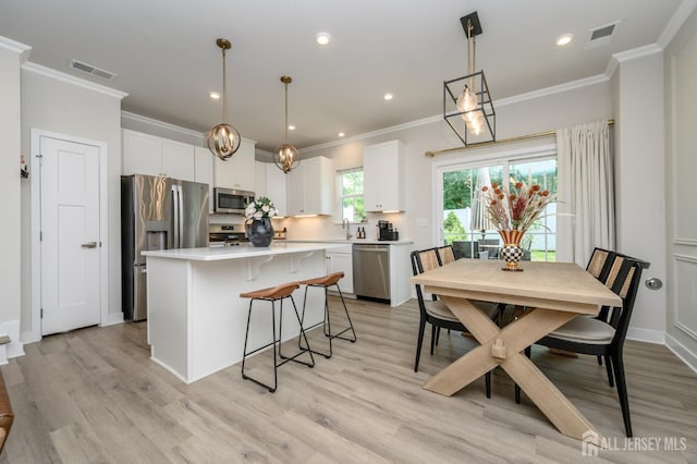 45 Athens Way, Aberdeen, NJ 07721 - kitchen featuring appliances with stainless steel finishes, a center island, crown molding, light countertops, and a breakfast bar