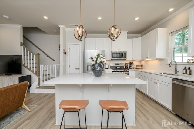 45 Athens Way, Aberdeen, NJ 07721 - kitchen with appliances with stainless steel finishes, light wood-style flooring, a kitchen island, a kitchen bar, and crown molding