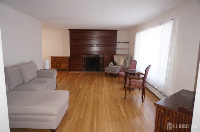 living room featuring light wood-type flooring and a brick fireplace