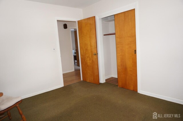 unfurnished bedroom with a closet, carpet flooring, and baseboards