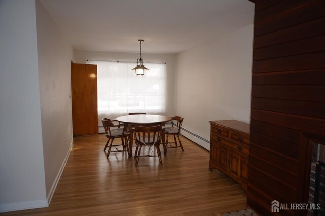 dining room featuring a baseboard radiator, baseboards, and wood finished floors