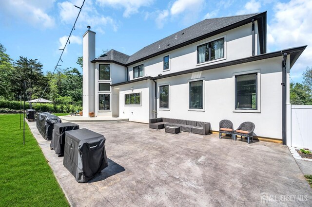 36 School Rd E, Marlboro, NJ 07746 - rear view of property featuring stucco siding, a chimney, a patio area, a lawn, and an outdoor living space