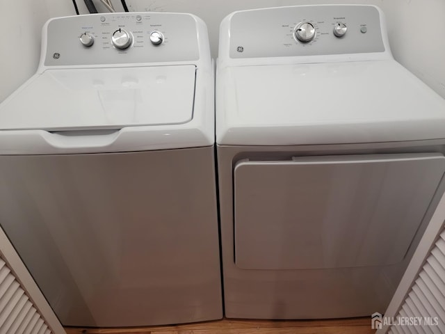 washroom featuring laundry area, washing machine and dryer, and wood finished floors