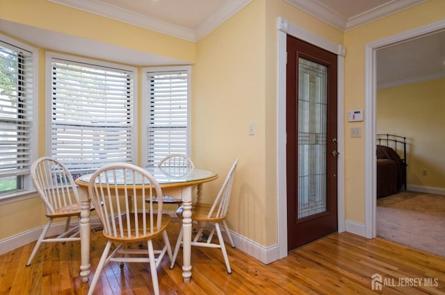 dining space featuring baseboards, ornamental molding, and wood finished floors