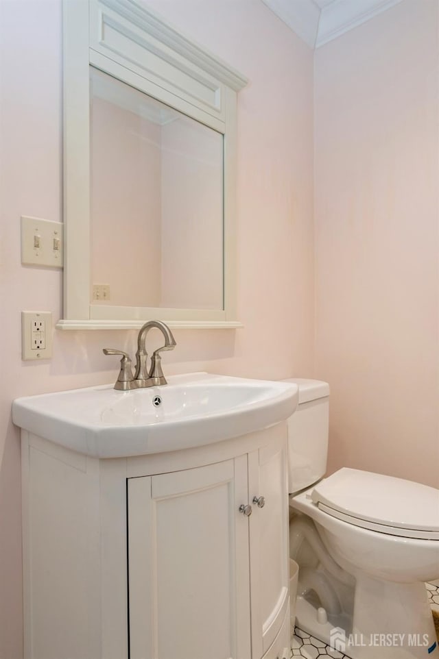 bathroom featuring toilet, ornamental molding, and vanity