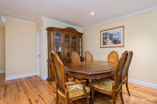 dining space with crown molding, baseboards, and light wood finished floors