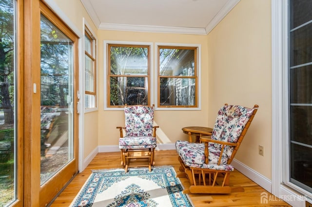 sunroom with plenty of natural light, ornamental molding, and wood finished floors