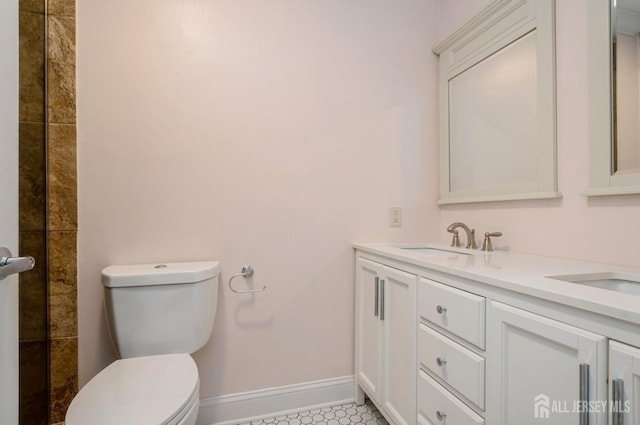 full bath featuring double vanity, toilet, baseboards, and a sink