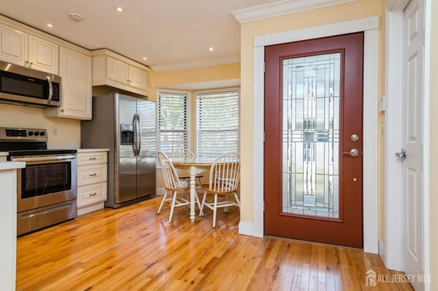 kitchen with crown molding, light wood-style floors, light countertops, cream cabinets, and appliances with stainless steel finishes