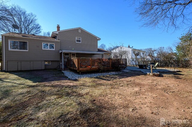 rear view of property featuring a lawn and a deck