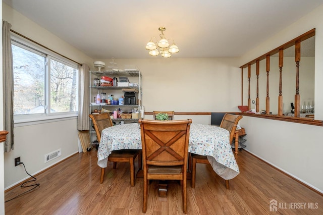 dining area featuring wood-type flooring and a chandelier