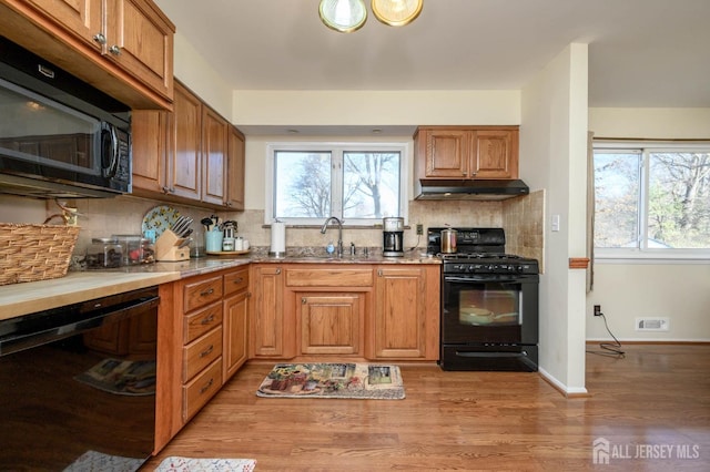 kitchen featuring sink, black appliances, tasteful backsplash, and light hardwood / wood-style flooring