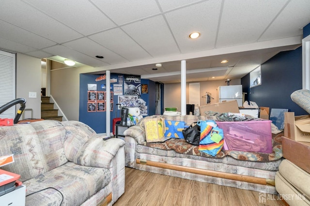 living room with a drop ceiling and wood-type flooring