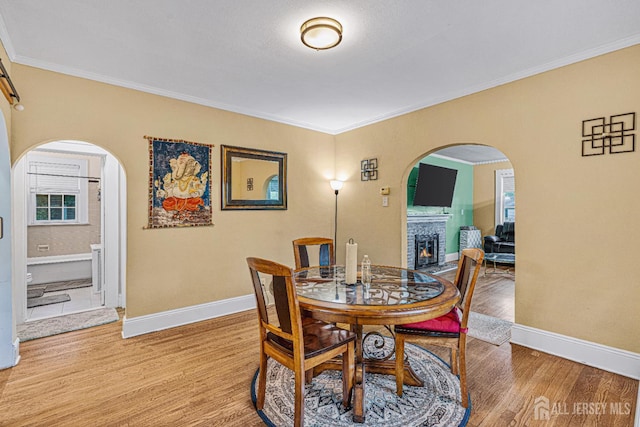 425 Grove Ave, Metuchen, NJ 08840 - dining area with arched walkways, light wood-style floors, baseboards, ornamental molding, and a lit fireplace