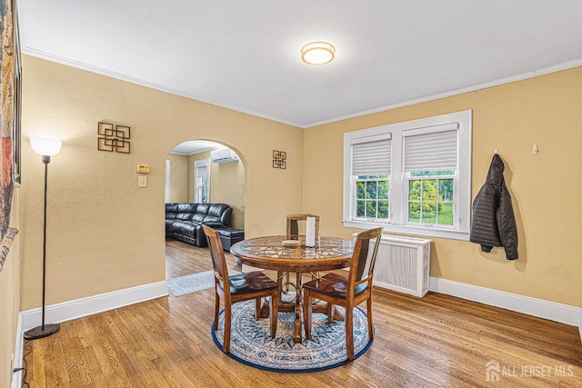 425 Grove Ave, Metuchen, NJ 08840 - dining room with arched walkways, wood finished floors, ornamental molding, a wall unit AC, and baseboards