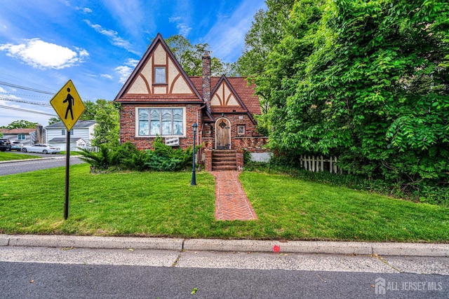 425 Grove Ave, Metuchen, NJ 08840 - tudor home with a chimney, a front lawn, and brick siding