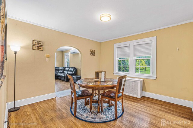 425 Grove Ave, Metuchen, NJ 08840 - dining space with arched walkways, an AC wall unit, light wood-type flooring, baseboards, and crown molding