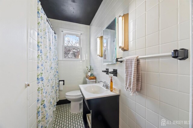 bathroom with toilet, vanity, tile walls, and walk in shower