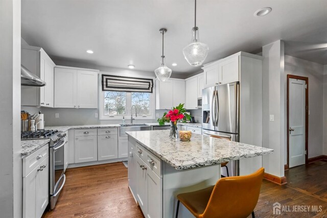 kitchen with a kitchen island, stainless steel appliances, white cabinets, and sink