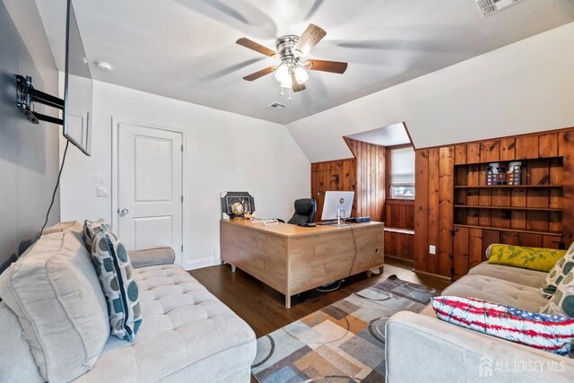 office space featuring ceiling fan, dark hardwood / wood-style floors, wood walls, and lofted ceiling